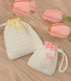 two crocheted bags sitting on top of a wooden table next to tulips