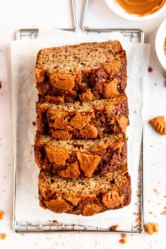 slices of chocolate chip banana bread on a cooling rack next to two cups of coffee