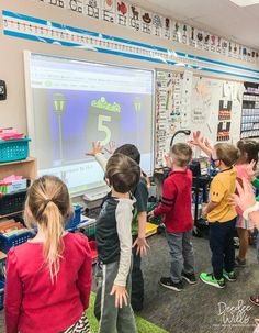 a group of young children standing in front of a whiteboard with numbers on it