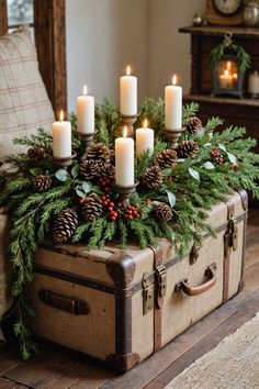 an old suitcase is adorned with pine cones and candles