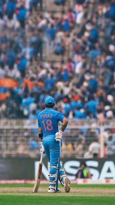 a man holding a cricket bat on top of a field in front of a crowd