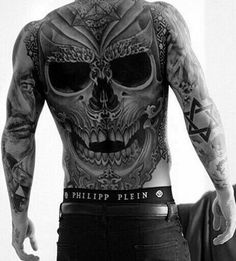 a man with tattoos on his back standing in front of a mirror next to a leather jacket