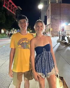 a man and woman standing on the sidewalk at night