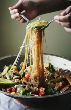 someone is eating noodles with chopsticks in a skillet