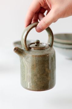 a person is holding a tea kettle in their hand and it has a small metal handle