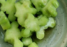 green vegetables are in a bowl with water droplets on the top and below it, as if they were cut into small pieces