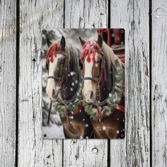 two horses with christmas wreaths on their heads are standing in front of a wooden fence