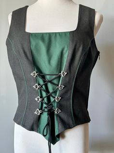 A Classic DIRNDL TRACHTEN VEST, Black with a Hunter Green Inset, 8 Metal Decorative Hooks and Black twisted cord are lacing the front, adjustable waist & bust, zipper on the side, side slits, lined in black silk like poly.  Material Wool, Poly and Elastan Blend, nice fabric, like a smoother gabardine cloth.  by "LAND HAUS, AUSTRIAN STYLE" Size 40 = US 10 VINTAGE, in excellent condition Green Sleeveless Festival Vest, Green Bohemian Cotton Vest, Chic Green V-neck Vest, Fitted Green V-neck Vest, Vintage Green Cotton Vest, Green Vest, Decorative Hooks, Vest Outfits, Hunter Green