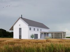 a large white building sitting in the middle of a field with birds flying over it