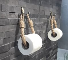 two rolls of toilet paper are hanging on the wall with rope attached to them,