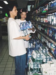 two people are looking at bottled water in a store