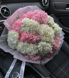 a bouquet of pink and white flowers sitting on top of a steering wheel in a car