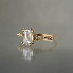 an engagement ring with a emerald cut diamond in the center and three small diamonds on each side