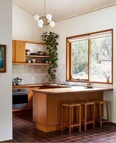 a kitchen with wooden cabinets and tiled flooring next to a window that has plants growing on it