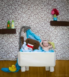 a baby laying in a crib with stuffed animals on the floor and wall behind it