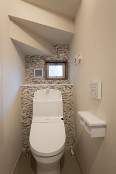 a white toilet sitting in a bathroom next to a window