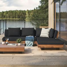 a couch sitting on top of a wooden floor next to a table and water in the background