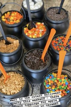 an assortment of desserts in black containers with orange spoons and candy on top