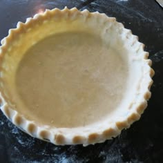 an uncooked pie crust sitting on top of a black table next to a knife