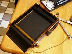 an open briefcase sitting on top of a wooden table next to scissors and other items