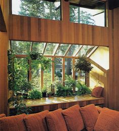 a living room filled with lots of furniture and plants on top of the windowsill