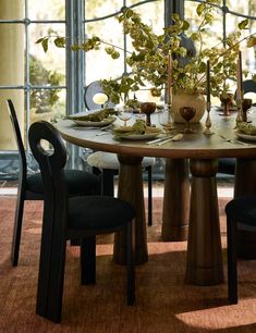 a dining room table with two chairs and a potted plant in the center on top