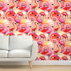 a white couch sitting in front of a wall with pink and orange flamingos on it