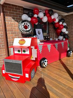 a red truck is parked in front of a birthday party decoration with balloons and streamers