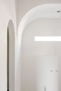 an empty room with white walls and arches