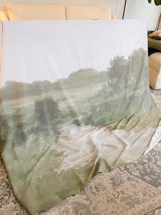 a painting is laying on the floor in front of a couch with pillows and blankets