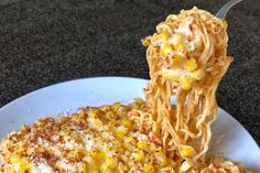 a spoon full of noodles with corn on top