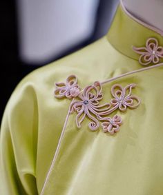 the back of a yellow dress with pink flowers on it's neck and shoulders