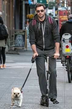 a man riding a scooter with a dog on a leash attached to it