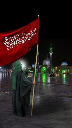 a person holding a red flag in front of a building with green lights on it