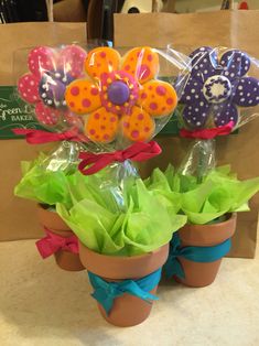 three flower pots filled with fake flowers in front of a brown bag on a counter