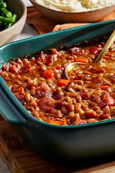 a green casserole dish filled with beans and meat