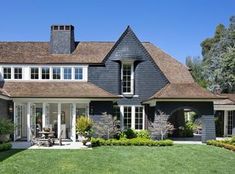 a large gray house with lots of windows and grass in front of the door area