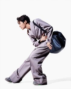 a man in grey suit and green shoes holding a black handbag on his back