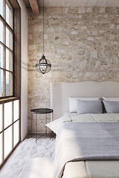 a bedroom with stone walls and flooring is pictured in this image, the bed has white linens on it