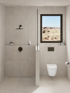 a white toilet sitting next to a shower in a bathroom under a large window on the side of a wall