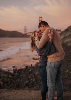 a man and woman embracing each other in front of the golden gate bridge at sunset