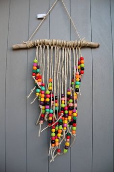 a multicolored beaded dream catcher hangs on a gray wall