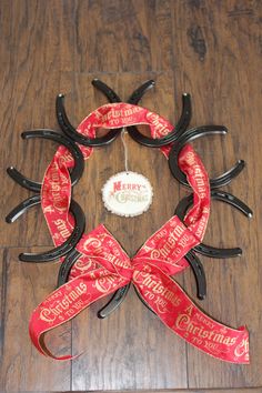 a christmas wreath made out of scissors and ribbon on a wooden floor with the words merry christmas written across it