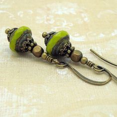 These not very large avocado green drop earrings are boho chic in style and dangle from brass earwires. The beads have a fantastic brownish patina and are faceted around their widest part to both give a clear view of their true color and add sparkle. The patina gives them an ancient, Green Artisan Dangle Earrings, Earthy Green Dangle Earrings, Bohemian Green Teardrop Jewelry, Earthy Green Drop Earrings, Green French Hook Earrings, Green Teardrop Bohemian Jewelry, Artisan Green Drop Earrings, Artisan Green Czech Glass Earrings, Bohemian Green Drop Earrings