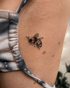 a small bee tattoo on the back of a woman's left arm and shoulder