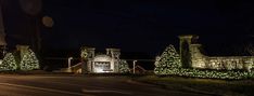 a street with christmas lights on it and trees in the front yard at night time