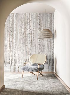 a chair sitting in front of a white wall with trees on the back and sides