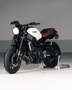 a white and black motorcycle is parked in a room with concrete flooring on the ground