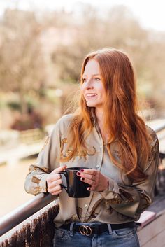 a woman with red hair is holding a coffee cup