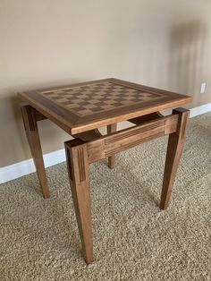 a wooden table with a chess board on the top and bottom piece sitting on carpeted floor